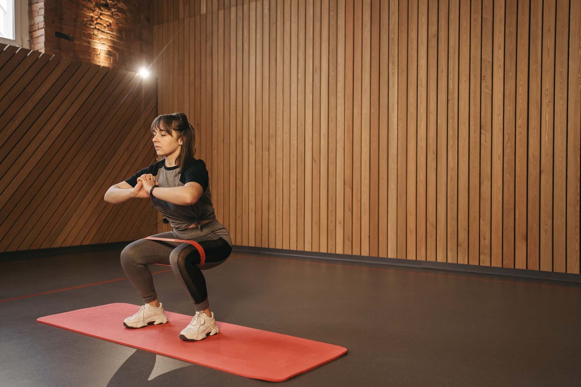 Woman doing a banded squat in a bright living room during an in-home training session