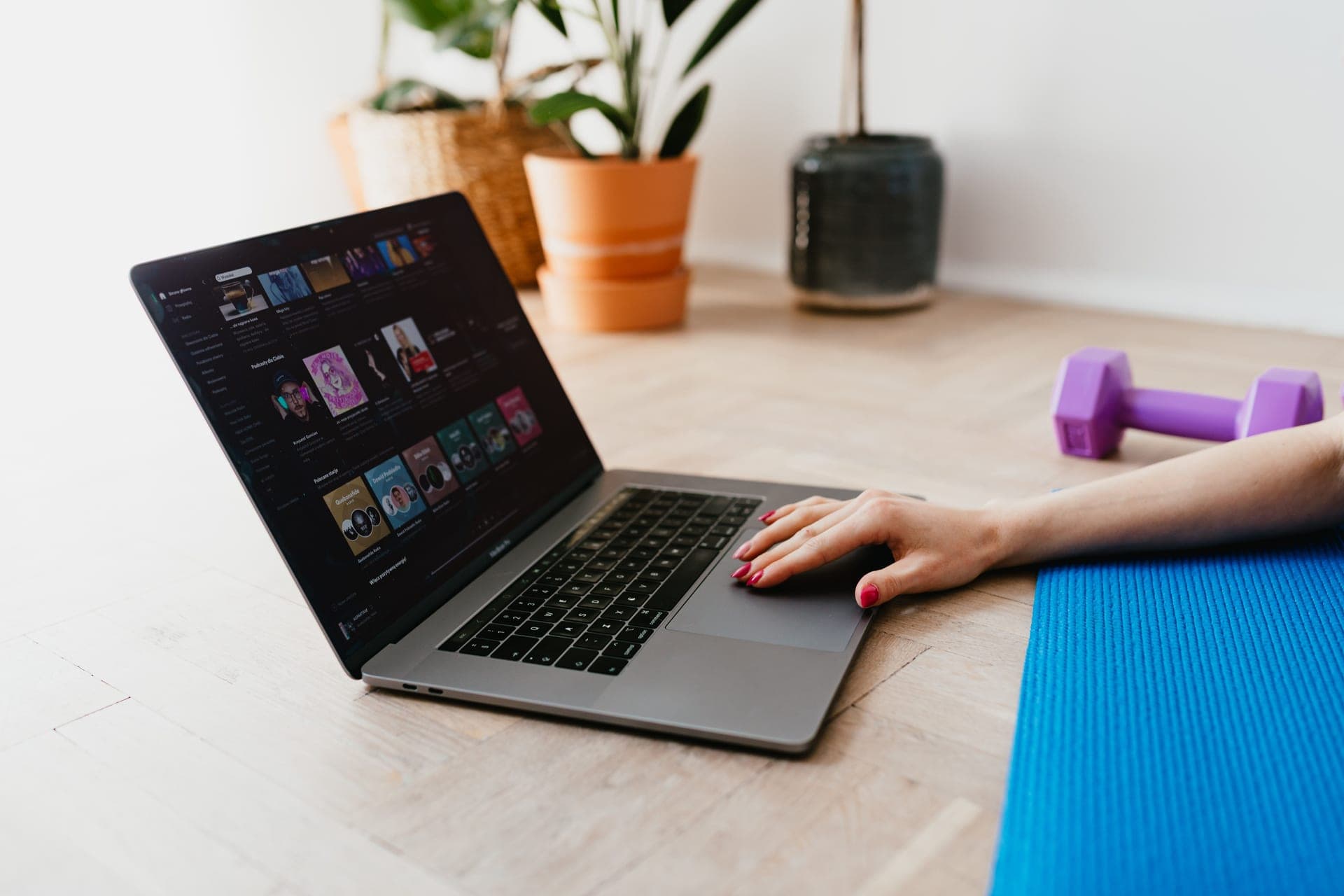 Laptop, water bottle, and dumbbells set up on the floor for an online coaching session