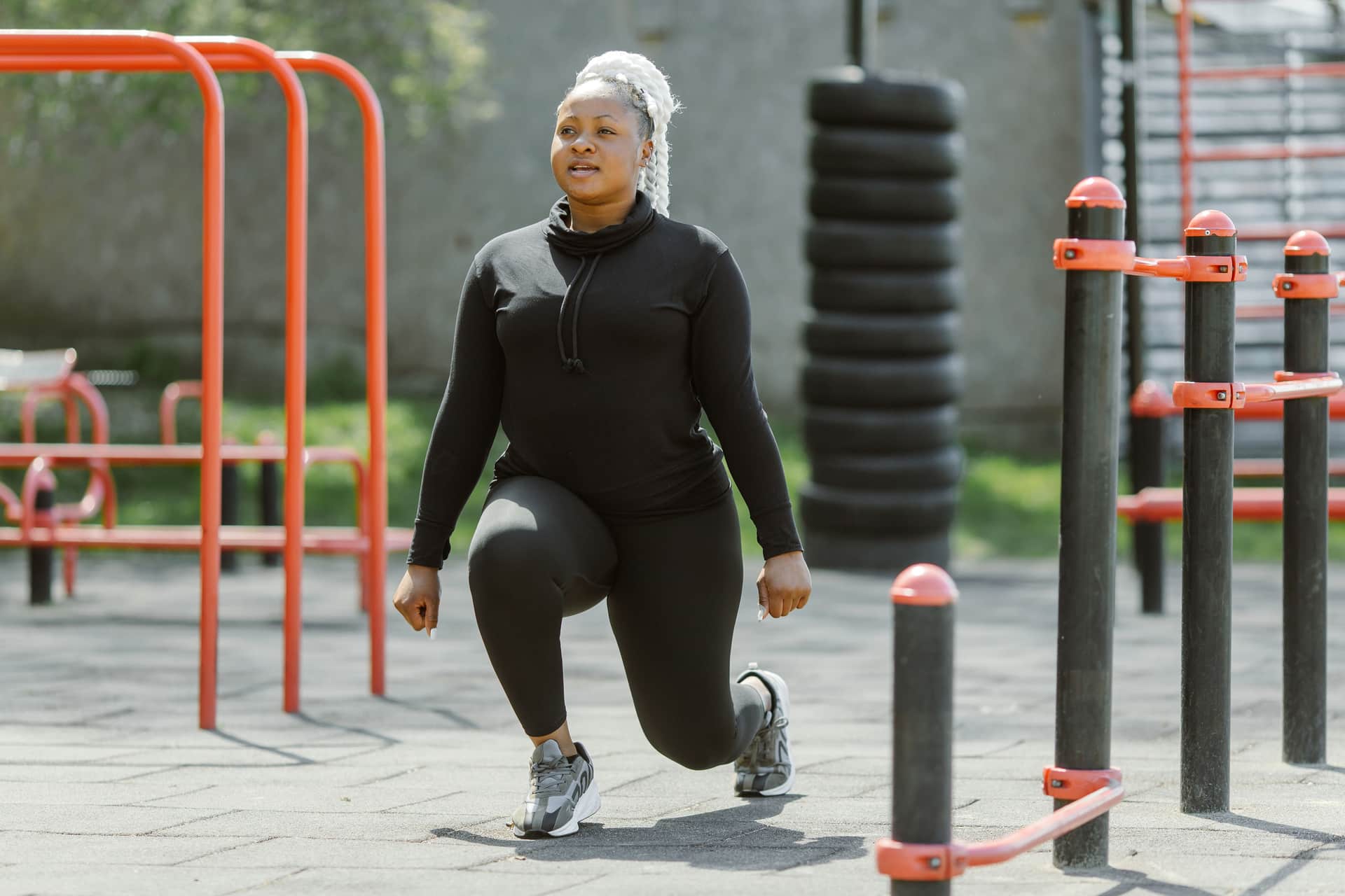 Woman doing a walking lunge at an outdoor park fitness area